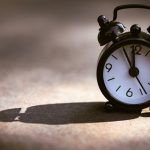 vintage alarm clock casting long shadow
