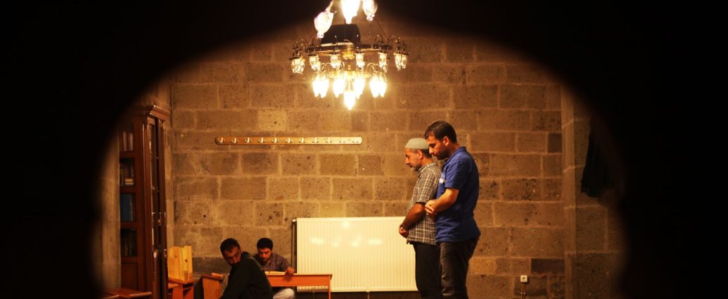 men praying inside a dimly lit mosque