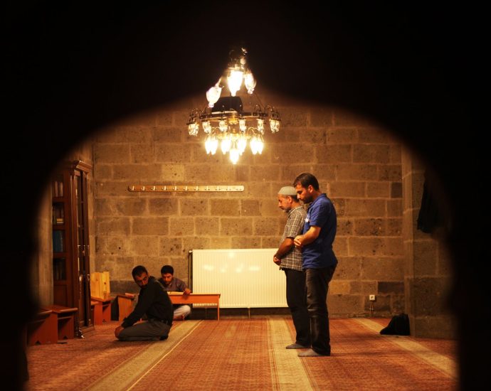 men praying inside a dimly lit mosque