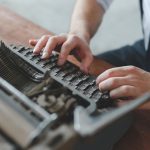 person typing on typewriter