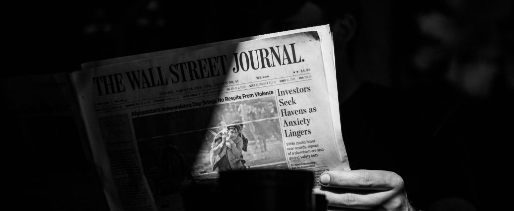 grayscale photo of a person holding a newspaper