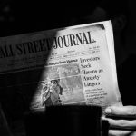 grayscale photo of a person holding a newspaper