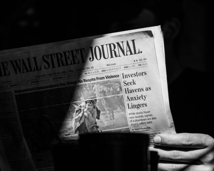 grayscale photo of a person holding a newspaper