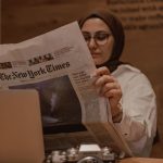 woman sitting at the table and reading a newspaper