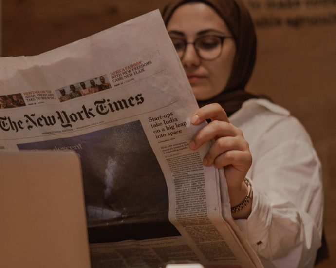 woman sitting at the table and reading a newspaper