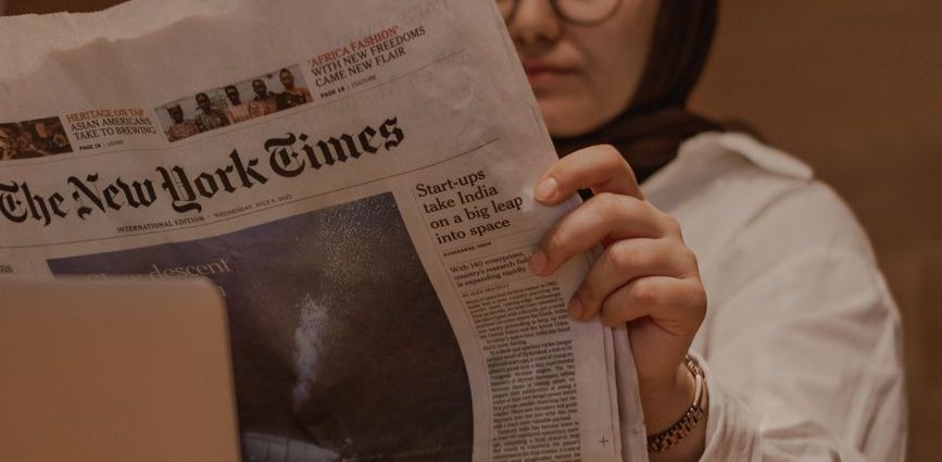 woman sitting at the table and reading a newspaper