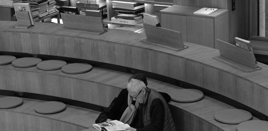 senior adult reading in modern library setting