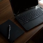 dark office workspace with laptop and notebook