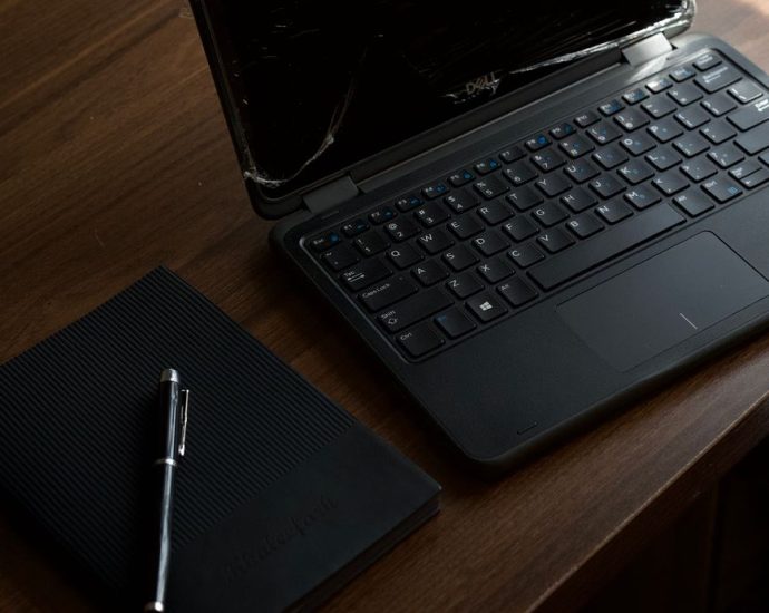 dark office workspace with laptop and notebook