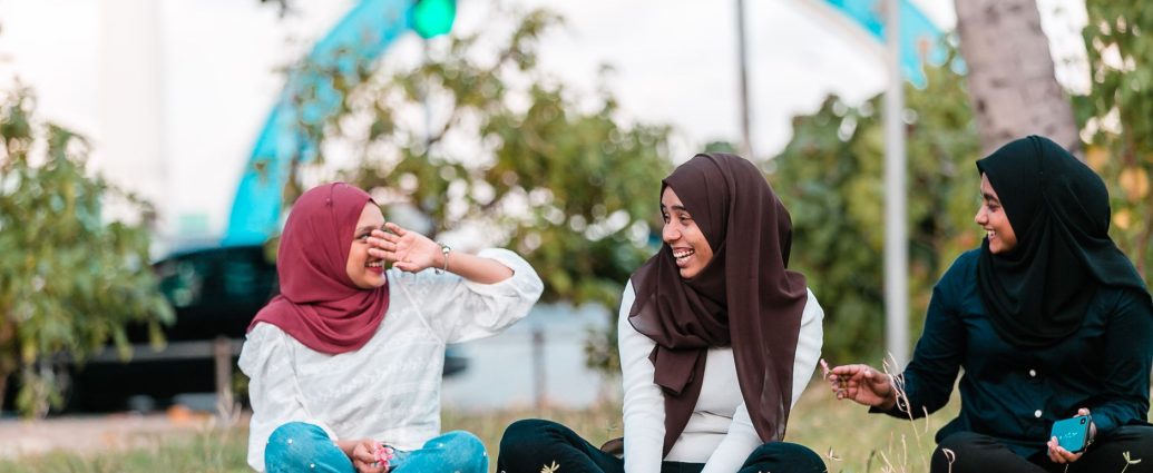 young muslim women laughing while resting on grass