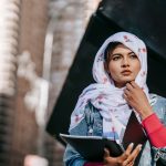 serious young woman in headscarf holding papers in folder