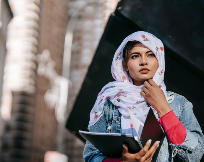 serious young woman in headscarf holding papers in folder