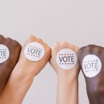 close up photo of vote stickers on people s fist