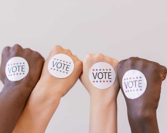 close up photo of vote stickers on people s fist